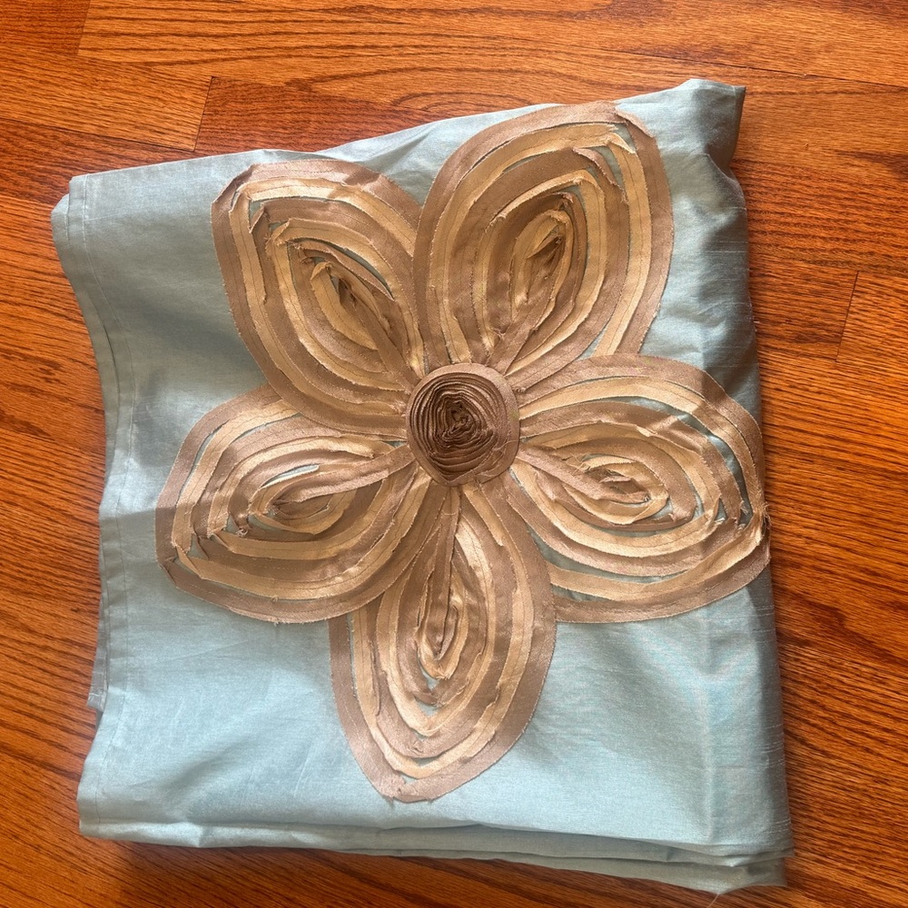 Fabric shower curtain in light teal with tan/gold flowers.